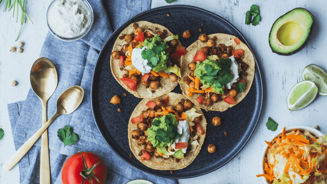  Colorful plate of three small tortillas filled with beans and veggies.